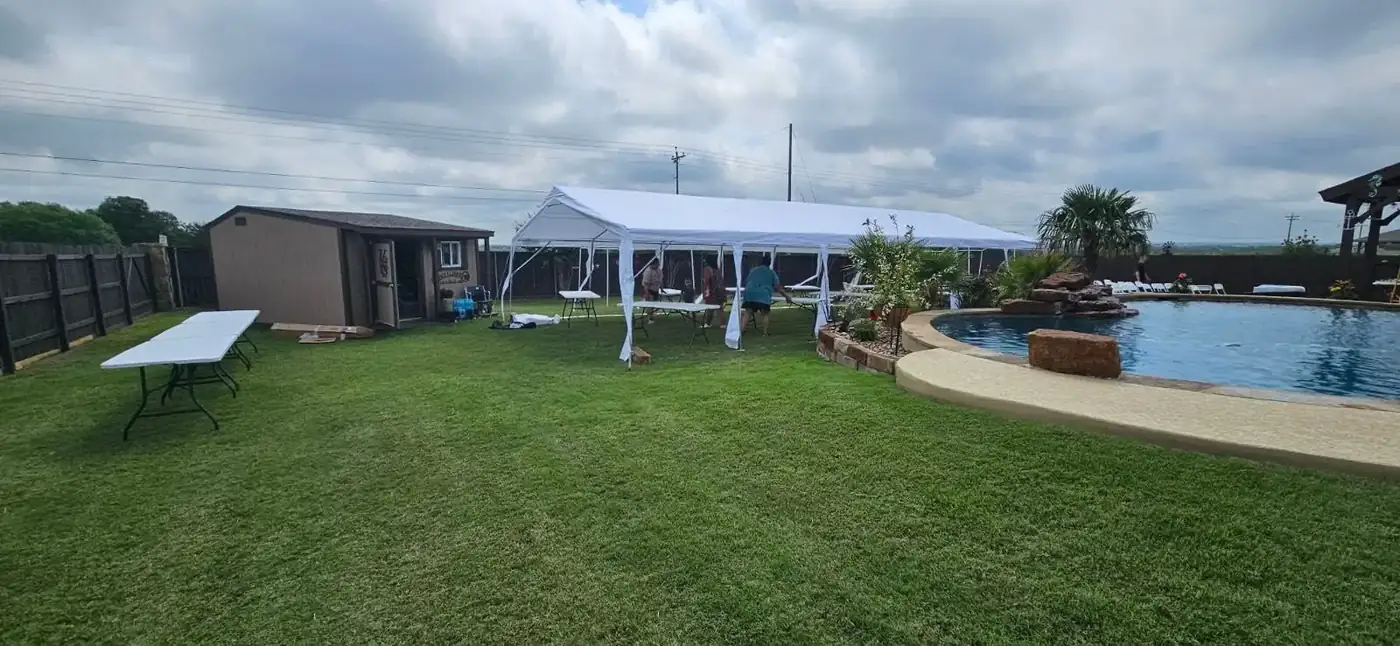 High peak tent in a backyard next to a pool
